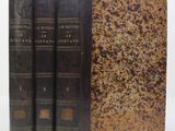 trois vieux livres posés l'un sur l'autre sur une surface blanche