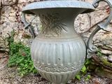 a large gray vase sitting in front of a stone wall