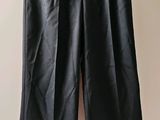 un pantalon en cuir noir suspendu à un cintre devant un mur blanc