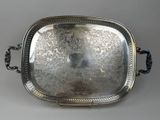 un plat ancien en argent avec des poignées, sur fond gris
