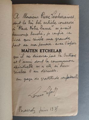 un livre ouvert, sur lequel est inscrit un poème manuscrit, posé sur une table