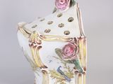 a white vase with pink roses on it on a table