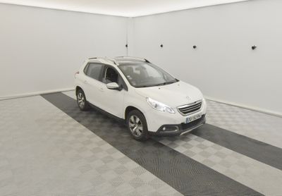 La petite voiture blanche est garée dans le garage de la maison.