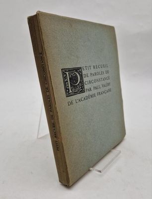 an old book sitting on top of a white table next to a glass stand