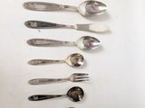 several spoons and forks are arranged in a row on a table