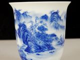 a blue and white cup with a mountain scene on it