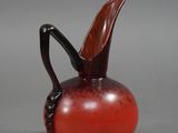 une image représentant un vase en verre rouge muni d'une anse noire