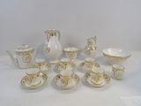 a white and gold tea set on a white table