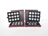 two sets of silver coins in a wooden case on a white background