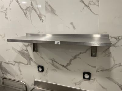 a stainless steel sink in a bathroom with marble walls