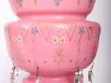 a pink bowl with beads hanging from it on a stand