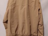 a brown jacket hanging on a hanger against a white wall