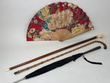 deux parapluies, une canne et un éventail posés sur une table