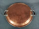 a large copper plate with a handle on a table