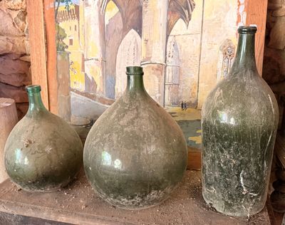 trois vases posés sur une étagère devant un tableau