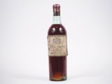 une vieille bouteille de vin posée sur une surface blanche