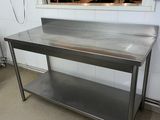 une table en acier inoxydable avec un miroir accroché au mur
