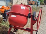 a red cement mixer sitting in front of a house