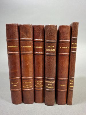 six livres en cuir marron alignés les uns à côté des autres sur une surface blanche