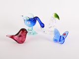 trois oiseaux en verre posés les uns à côté des autres sur une surface blanche
