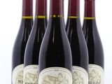 quatre bouteilles de vin rouge sont alignées sur une surface blanche