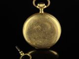 an antique gold pocket watch with a key on a black background