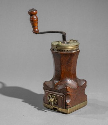 an old coffee grinder with a wooden handle on a gray surface