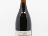 the bottle of red wine is sitting on a white surface