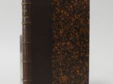 an old book with a brown cover sitting on top of a white surface
