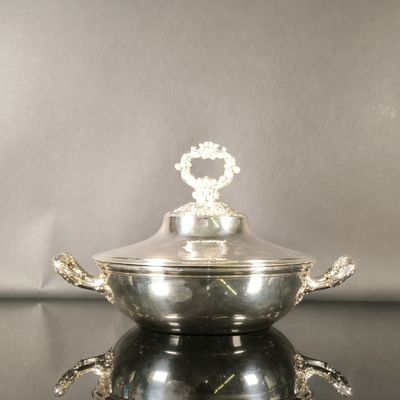 un bol en argent avec un couvercle posé sur une table noire