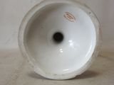 a white vase with a black spot in it