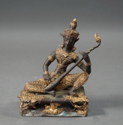 a bronze statue of a man playing a musical instrument on a rock