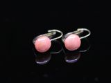 pair of pink stone earrings on black surface with reflection