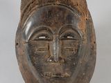 an image of a wooden mask on a stand on a white surface