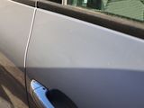 a cat sitting on the door of a car looking out the window