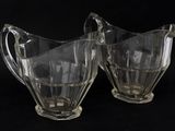 two clear glass pitchers on a black background with a black background