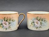 two cups with flowers painted on them are sitting on a table