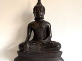 une statue de Bouddha noire posée sur une surface blanche