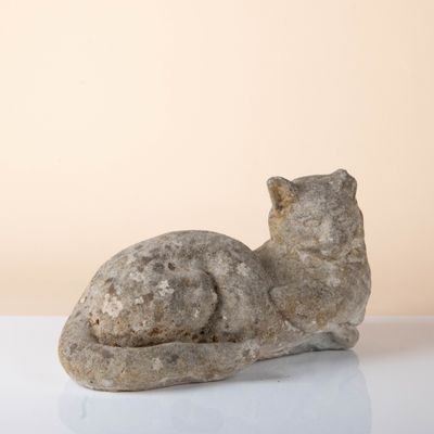 sculpture représentant un chat assis sur une surface blanche, sur fond beige