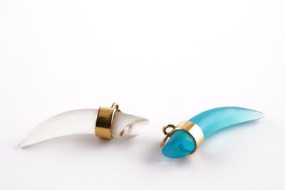 une paire de boucles d'oreilles turquoise et dorées sur fond blanc