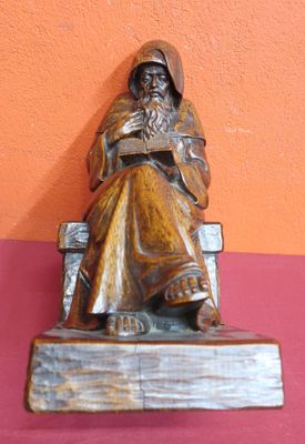 statue d'un vieil homme assis sur un banc en train de lire un livre