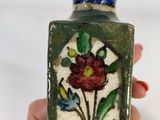someone is holding a small bottle with a flower design on it