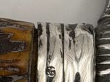 a close up of a silver and wood object on a table