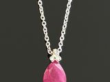 a close up of a necklace with a pink stone on a chain