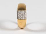 gros plan d'une bague en or avec des diamants sur une surface blanche