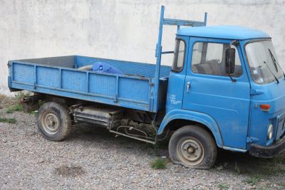 a blue truck parked in front of a white wall