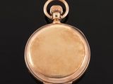 a close up of a gold pocket watch on a black surface