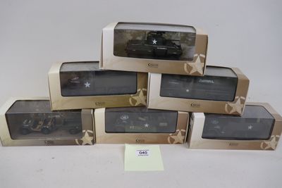 six modèles réduits de voitures militaires dans leurs boîtes, posés sur une surface blanche