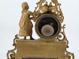 a gold clock with a man and a woman on it