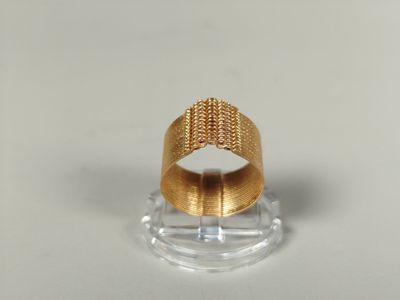 un gros plan d'une bague en or posée sur un socle transparent